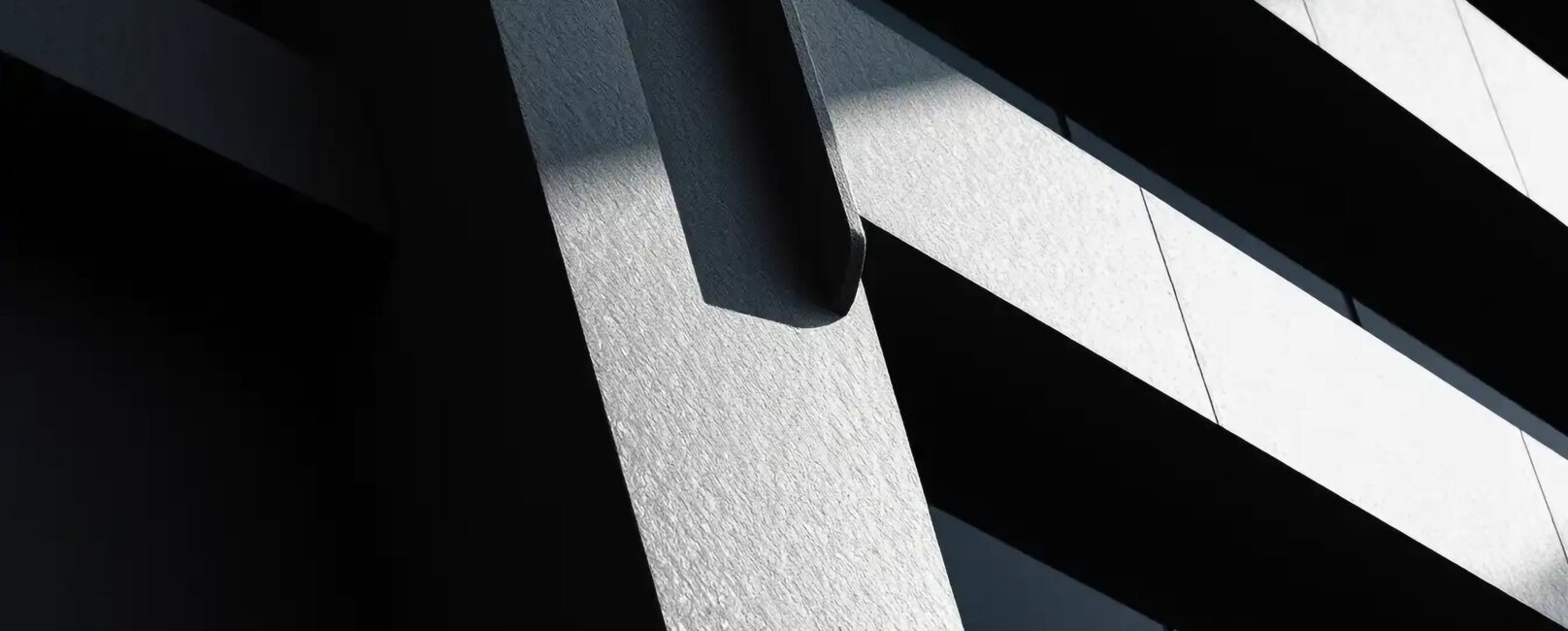 Abstract architectural lines and shadows create a dramatic contrast of light and dark on a textured surface