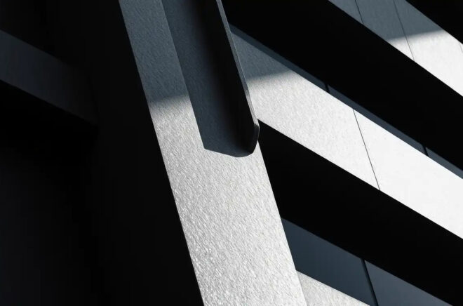 Abstract architectural lines and shadows create a dramatic contrast of light and dark on a textured surface
