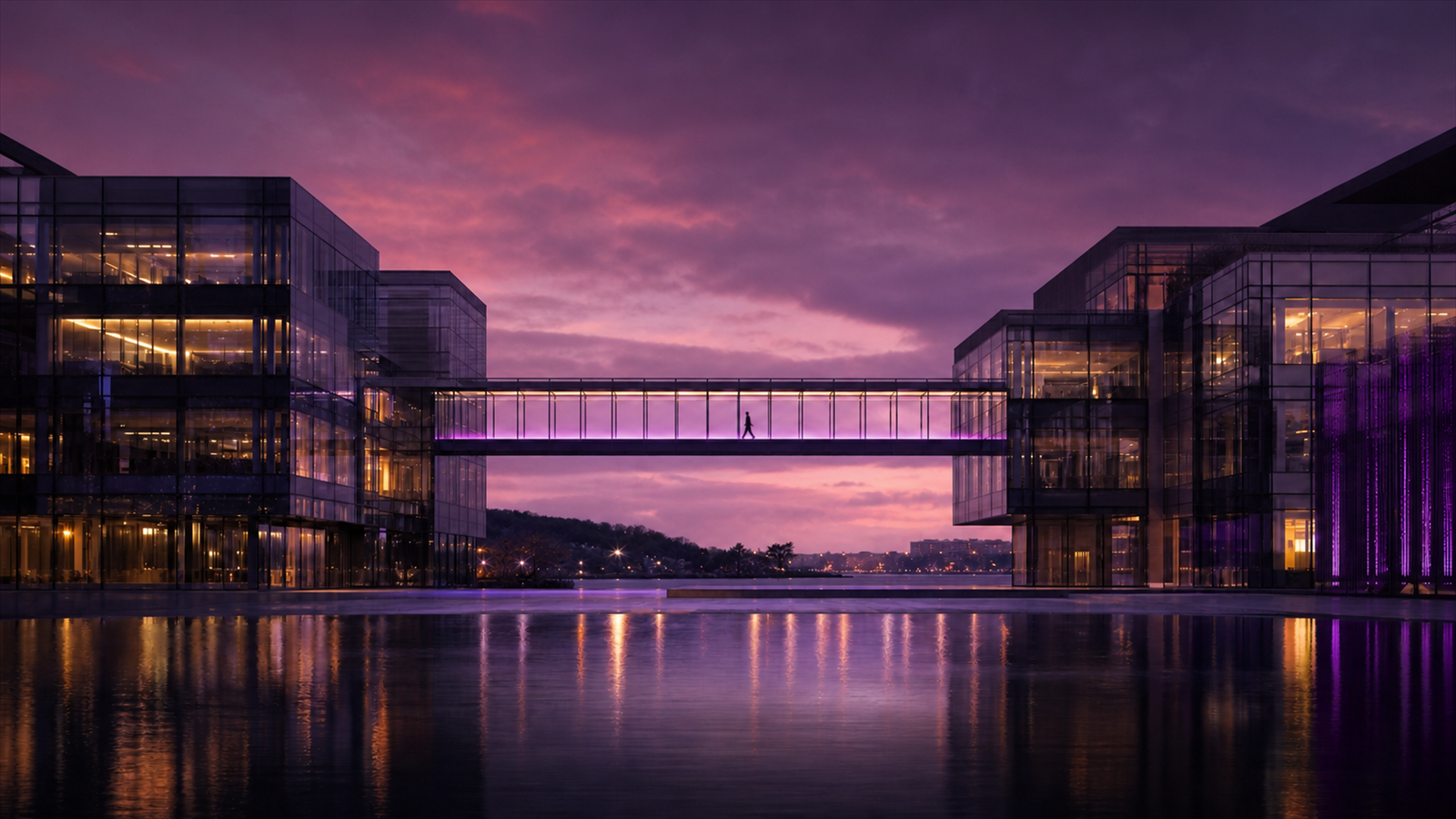 Figure crossing an illuminated skybridge between modern office buildings at purple dusk.