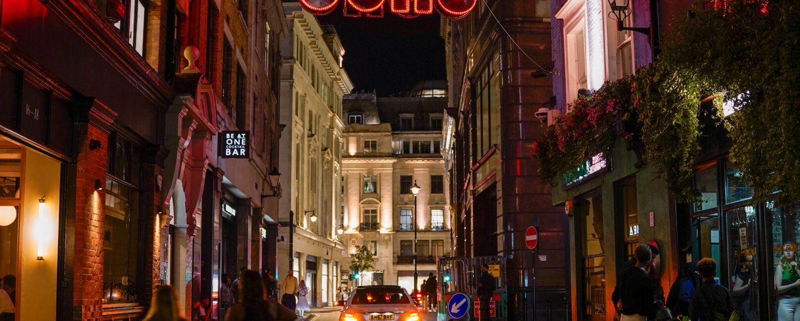 Illuminated Soho sign above a London street at night
