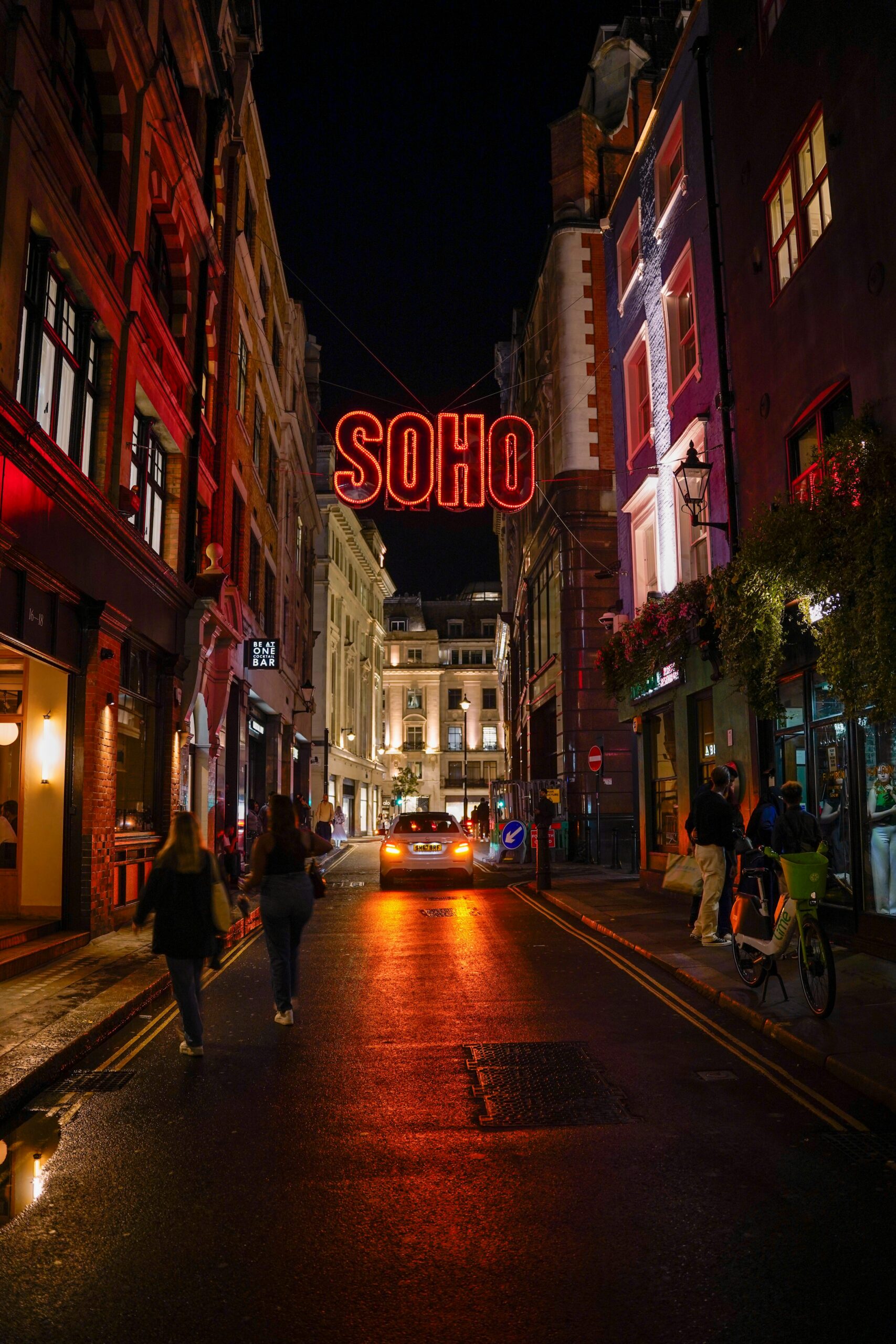 Illuminated Soho sign above a London street at night